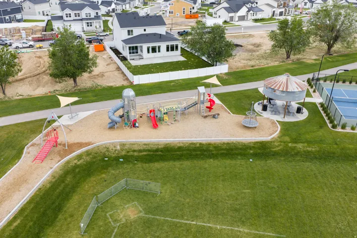 Community green space featuring a playground, tennis court, and covered seating area