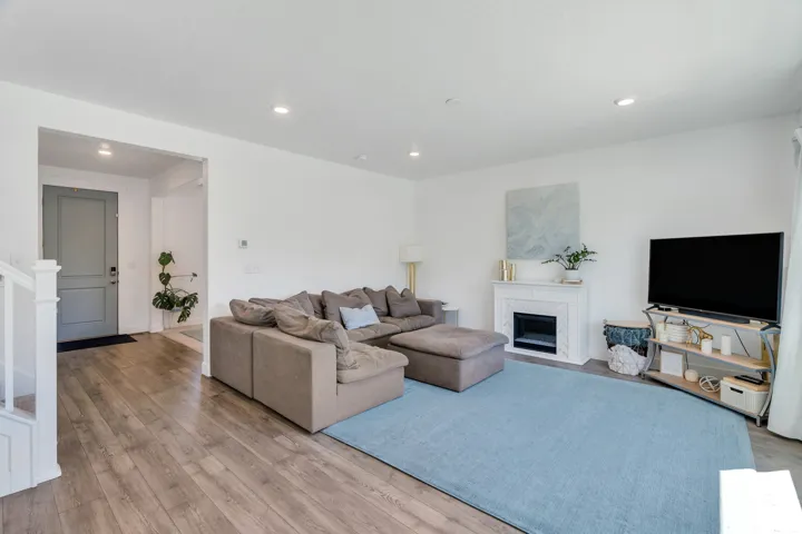 Open-concept living area featuring wood-finish flooring, recessed lighting, and a modern fireplace with a detailed mantel