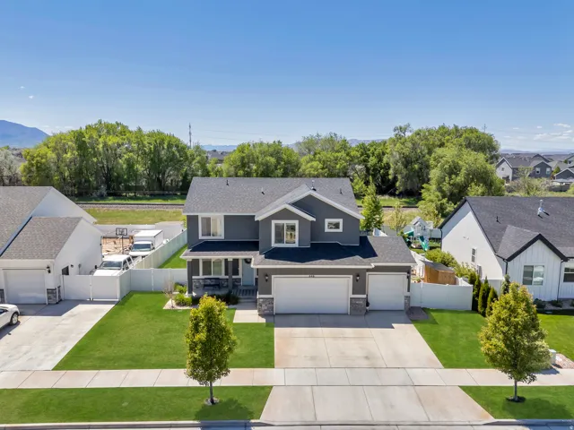 Two-story residence featuring a gray exterior with stone accents, a two-car garage, and a manicured front lawn