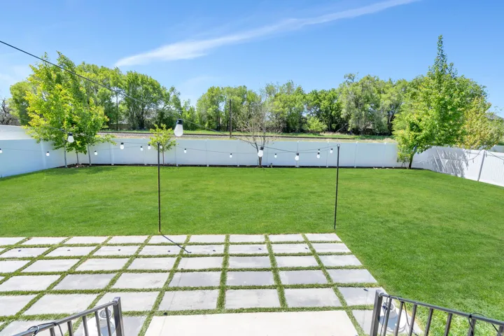Expansive green lawn framed by a white privacy fence