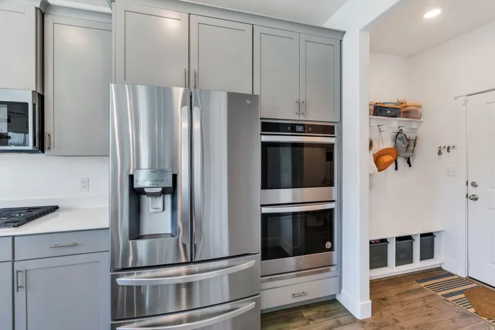 Stainless steel French door refrigerator alongside double wall ovens