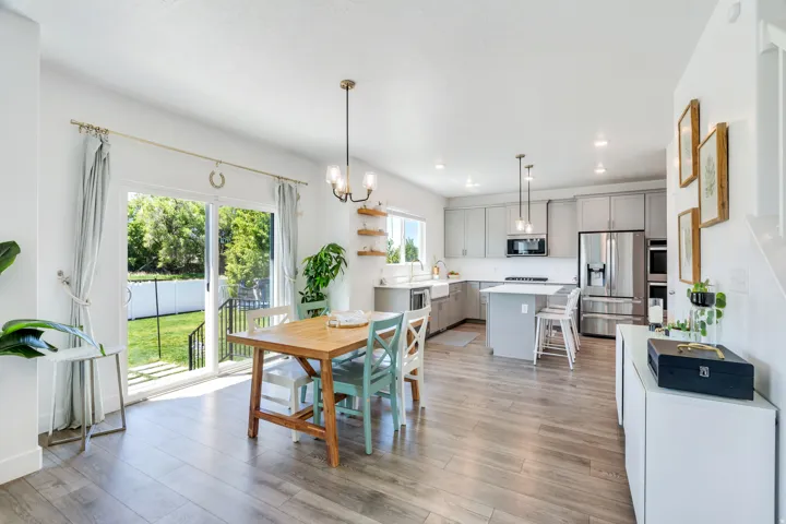 Open-concept living area featuring wood-finish flooring throughout, a modern kitchen with light gray cabinetry and stainless steel appliances, and a central island with bar seating