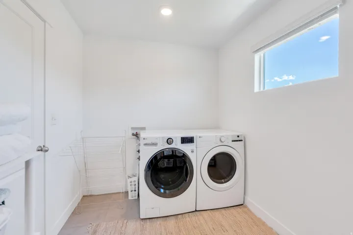 Dedicated laundry area featuring a front-load washer and dryer, recessed lighting, and a single window