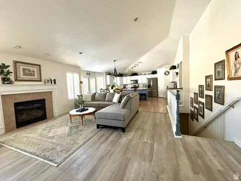 Living area featuring wood-finish flooring, a tiled fireplace with a mantel, and shuttered windows