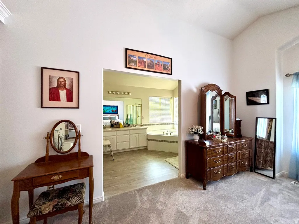 Vaulted ceiling room with carpet flooring and an arched doorway opening to a bathroom