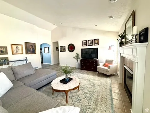 Spacious living area featuring a vaulted ceiling and wood-finish flooring