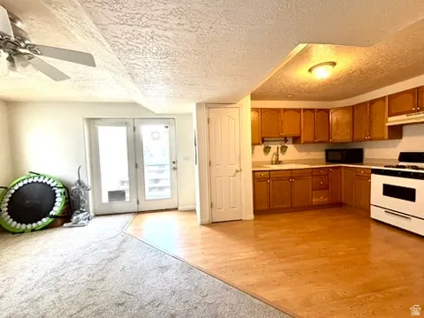 Open-concept room featuring a kitchen with wood-finish cabinetry, a corner sink, and a white range