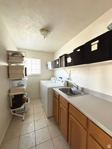 Laundry area featuring a utility sink, light wood cabinetry, and a light-toned countertop