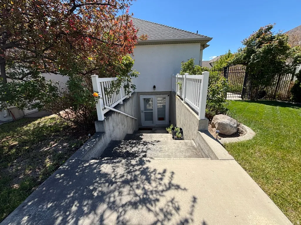Exterior concrete staircase providing separate access to the lower level, featuring white vinyl railings and a double glass-paned door entry
