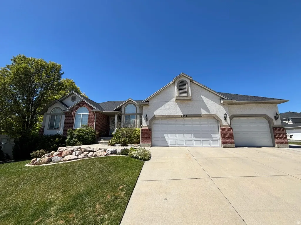 Stucco and brick exterior with arched windows, a multi-car driveway, and 3 car garage