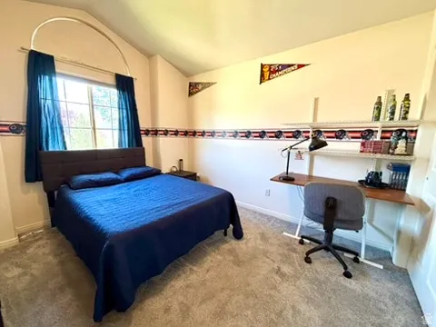 Carpeted room featuring a large arched window, vaulted ceiling, and built-in shelving