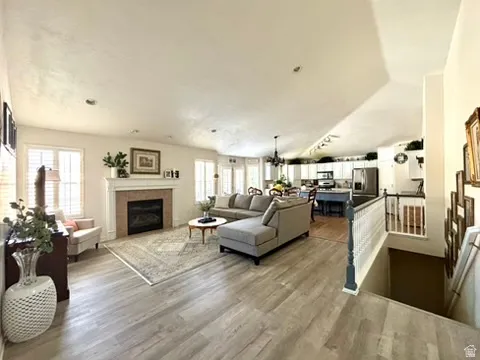 Spacious living area featuring wood-finish flooring, a fireplace with a detailed mantel, and recessed lighting