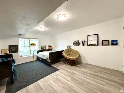 Spacious room featuring wood-finish flooring, a large window, recessed lighting, and a partial wall element