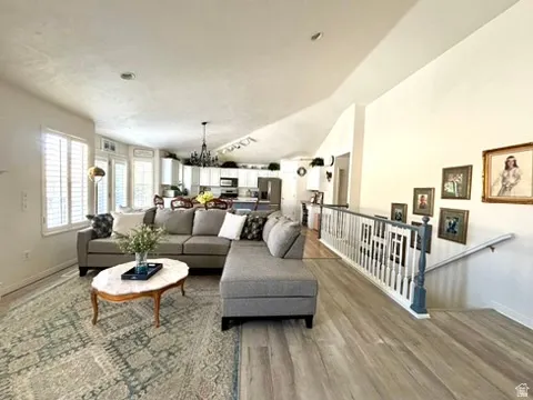Open-concept living area featuring wood-finish flooring, plantation shutters, and a vaulted ceiling