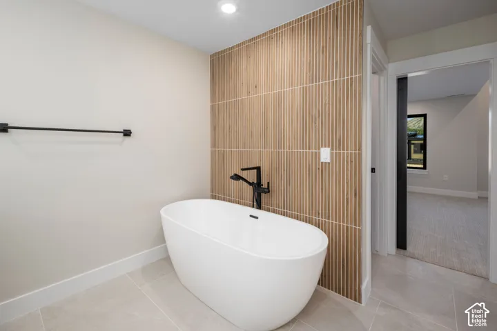Freestanding soaking tub with matte black floor-mounted faucet, complemented by a ribbed wood-finish accent wall