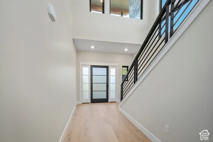 Contemporary entryway featuring light wood-finish flooring, a modern black metal staircase railing, and recessed lighting