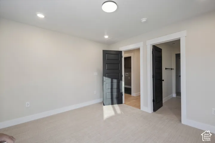 Spacious room featuring neutral carpeting, light-toned walls, and recessed lighting