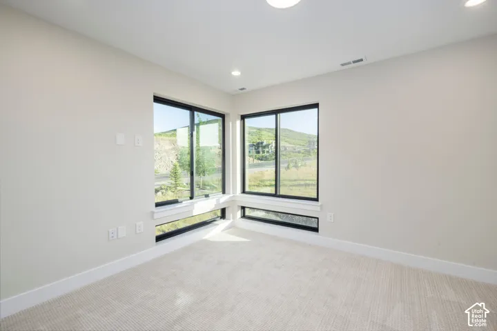 Corner window configuration with expansive mountain scenery, neutral carpeting, recessed ceiling lighting, and white baseboards