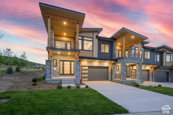 Contemporary multi-level exterior featuring stone cladding, wood-finish siding, and large windows