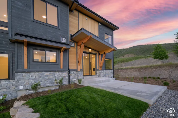 Contemporary architectural facade featuring dark horizontal siding, light wood-tone accents, and stone veneer foundation