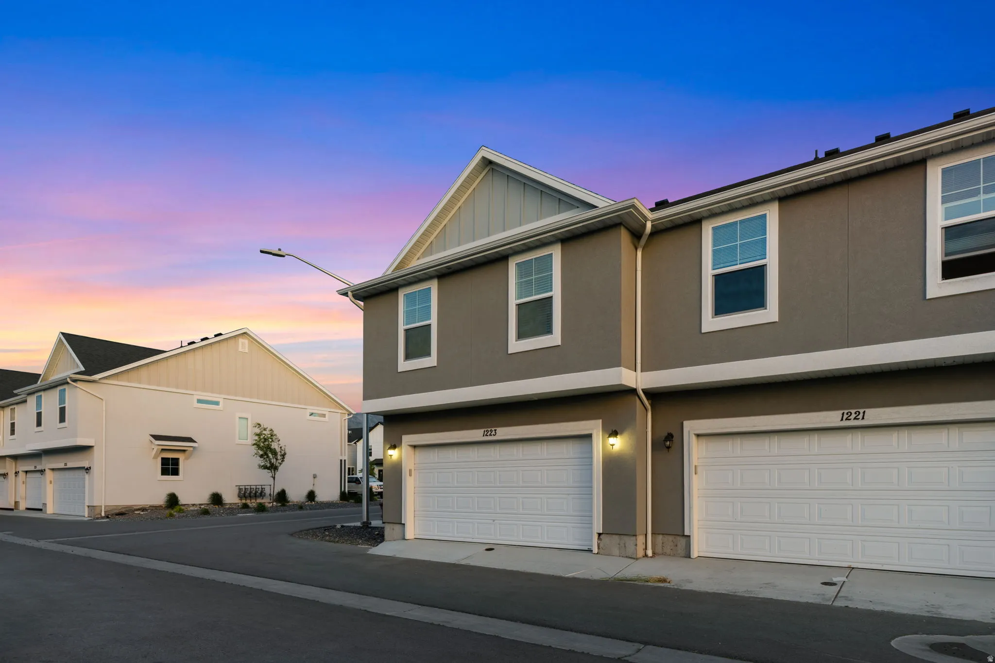 Contemporary townhome exterior featuring an attached two-car garage, stucco finish, and white-trimmed windows