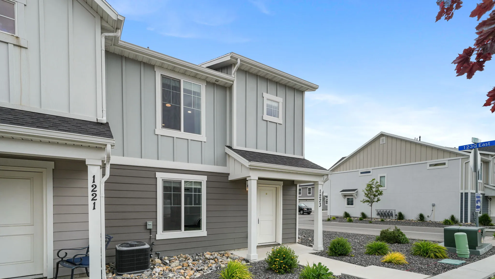 Contemporary facade featuring vertical and horizontal siding, white trim windows, and a covered entry