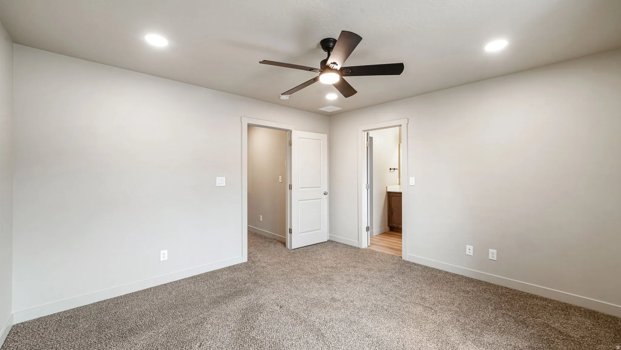 Carpeted interior room featuring a ceiling fan with light fixture, recessed lighting, and light-toned walls
