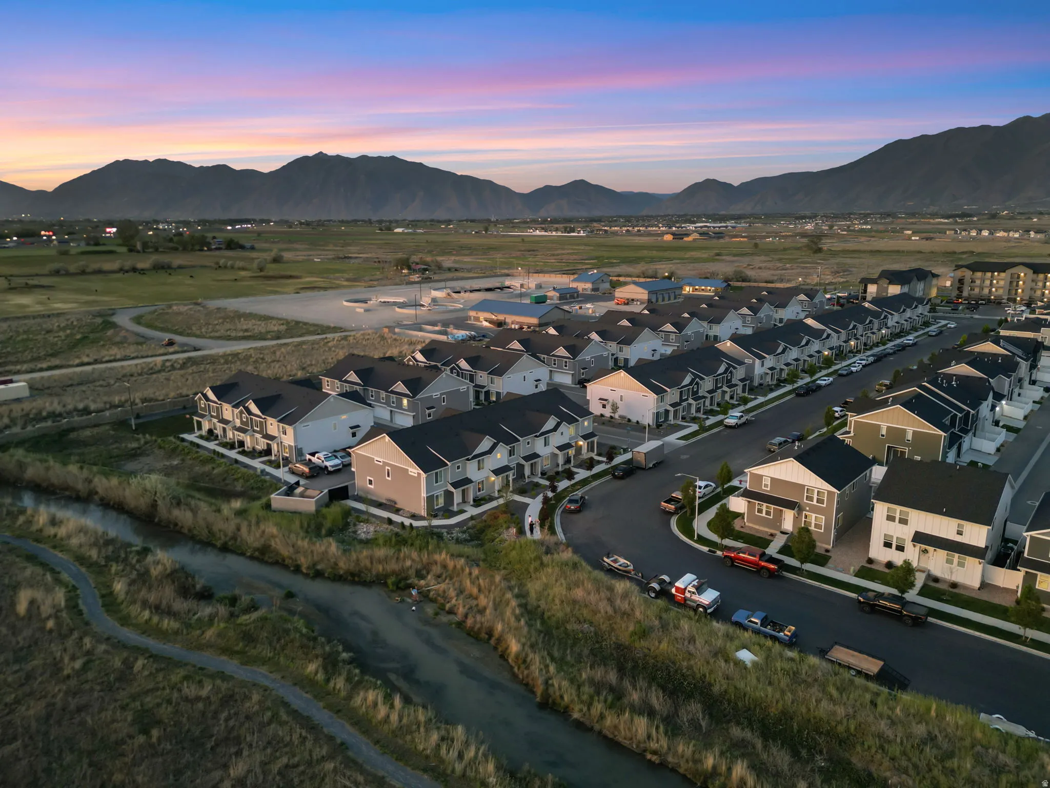 Residential neighborhood featuring a paved street, uniform housing styles, and mountain backdrop