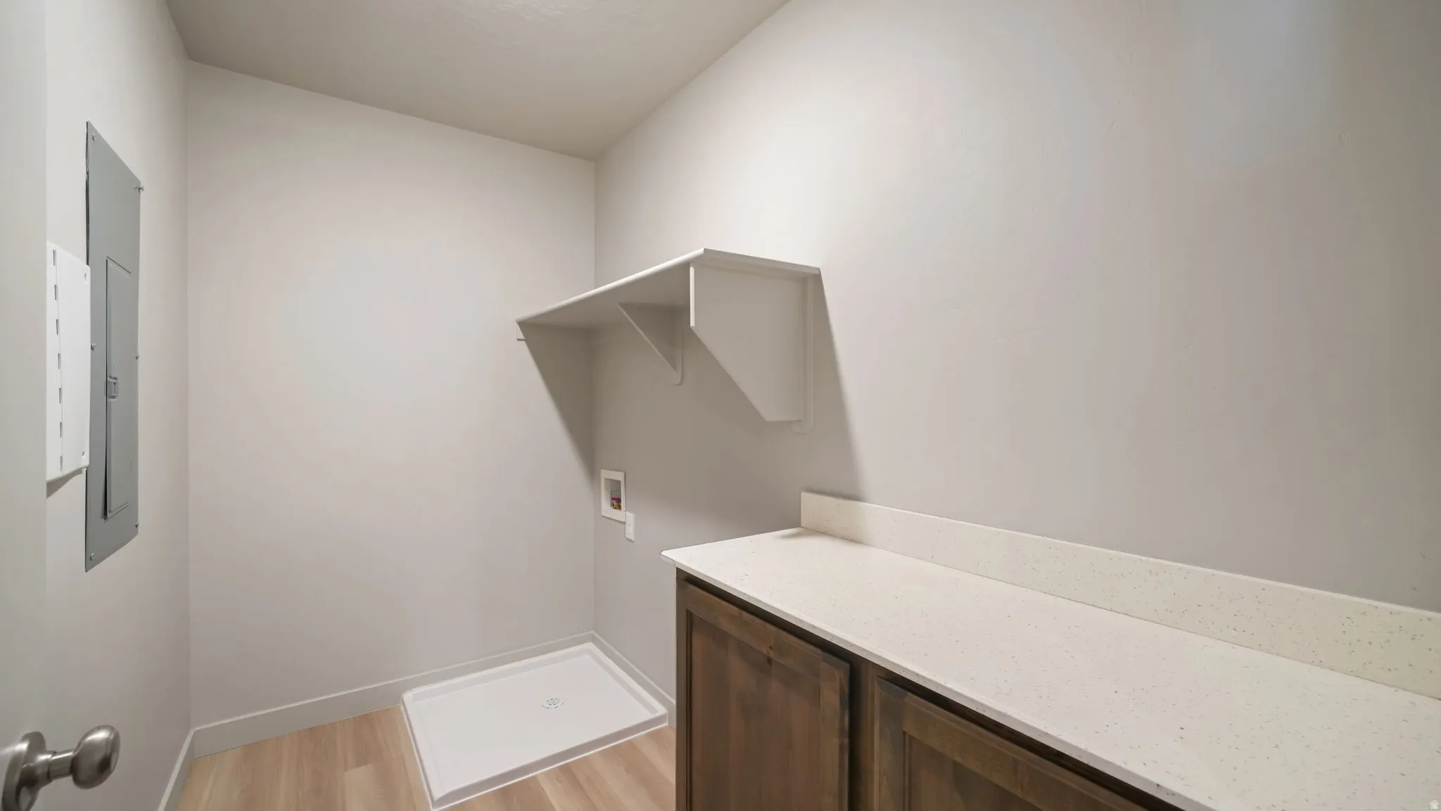 Utility room featuring wood-finish flooring, white walls, and a built-in shelf