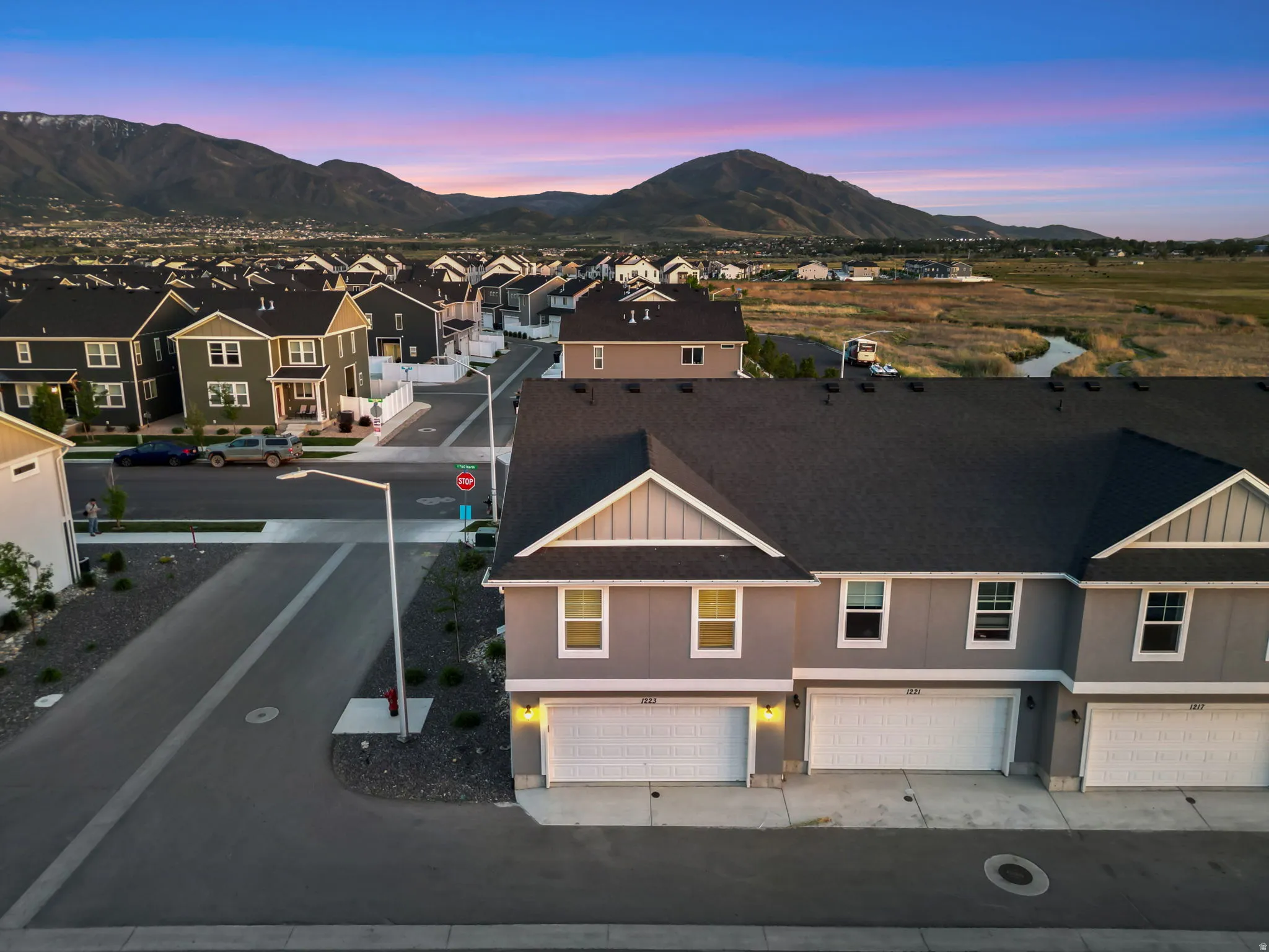 Modern townhome exteriors featuring multiple garages, a dark shingle roof, and light-toned siding