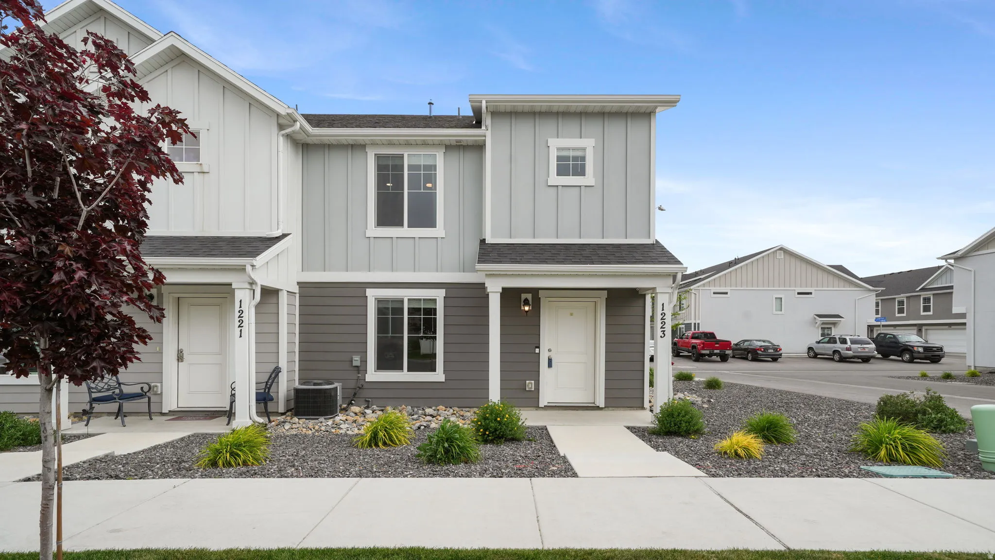 Modern townhome exterior featuring multi-toned siding, white trim, a covered entry, and a paved walkway
