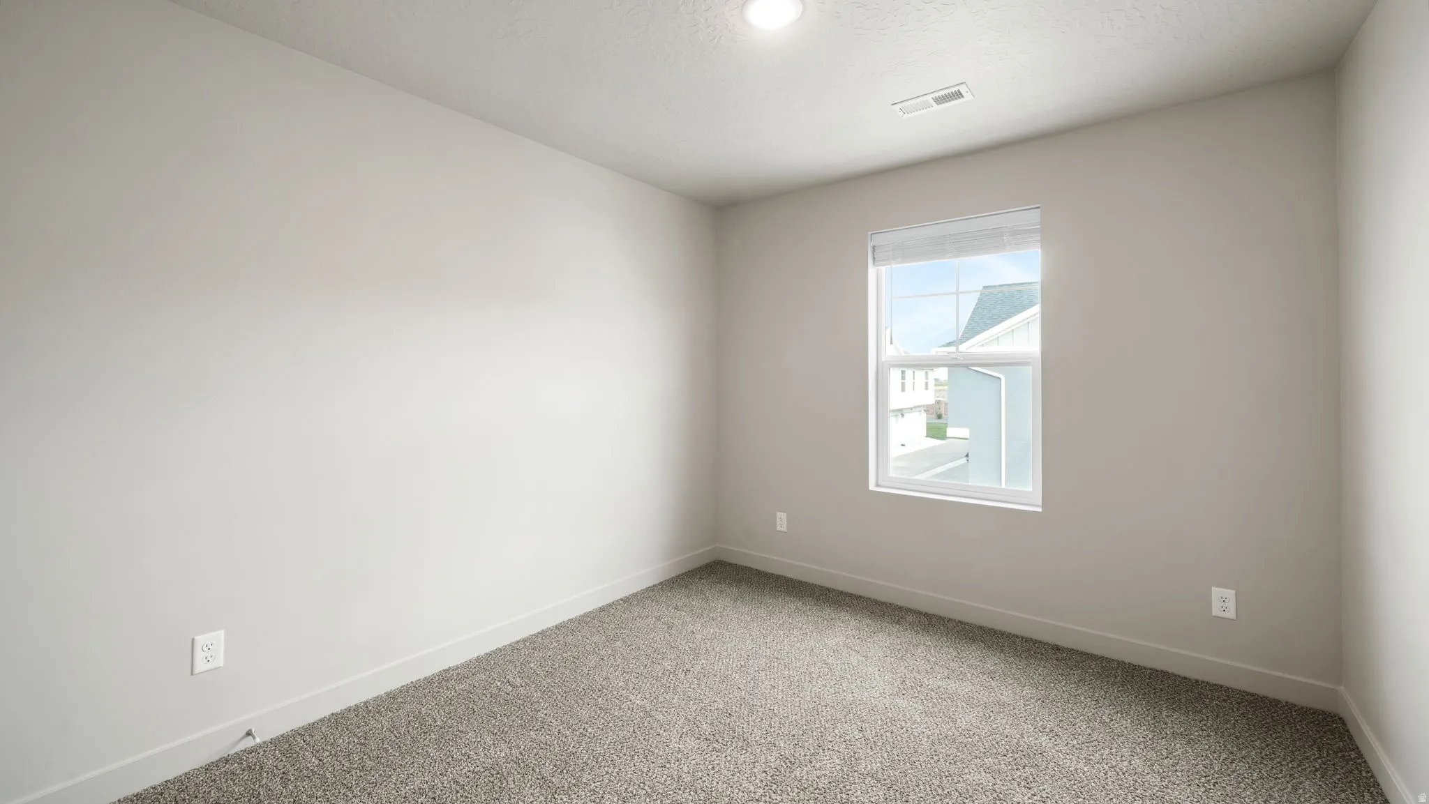 Carpeted interior room with neutral-toned walls, recessed ceiling light, and a single window