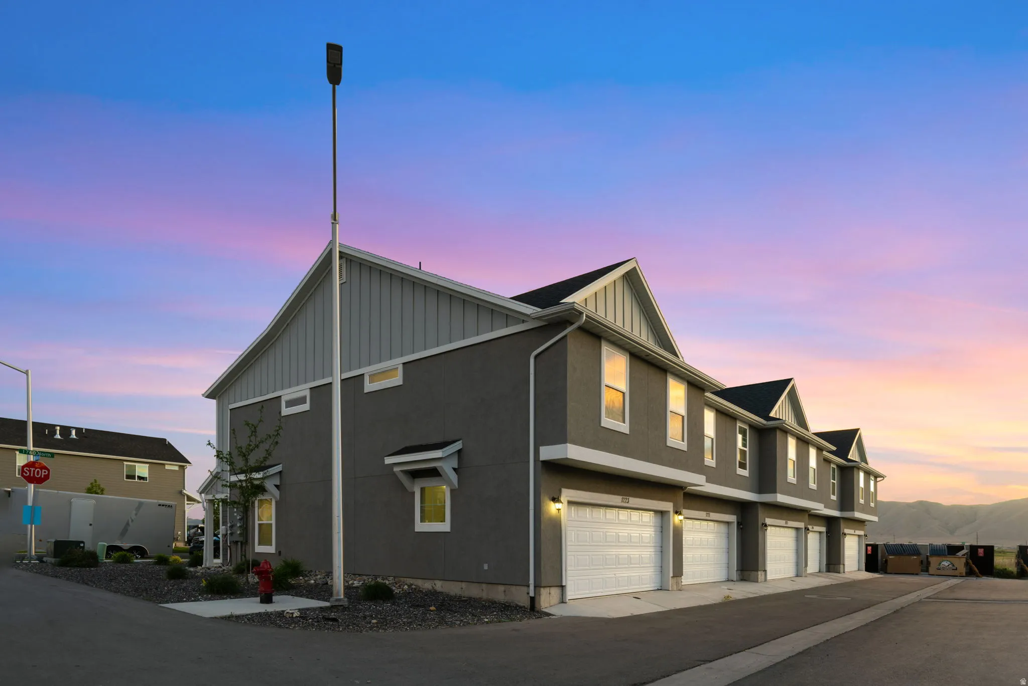 Contemporary multi-story townhome residences featuring a stucco and siding exterior, individual garages, and a paved driveway