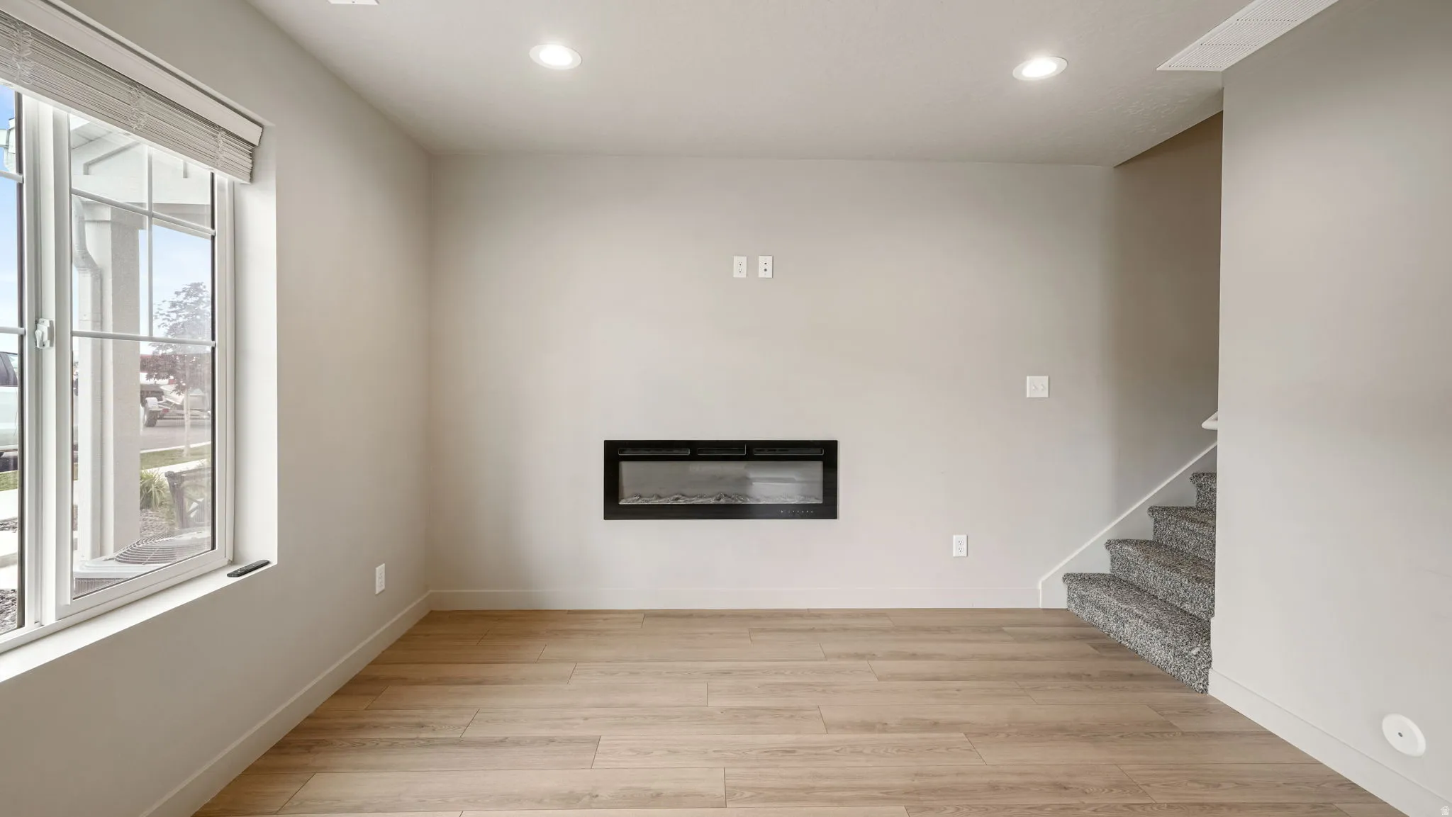 Spacious room featuring wood-finish flooring and an inset electric fireplace