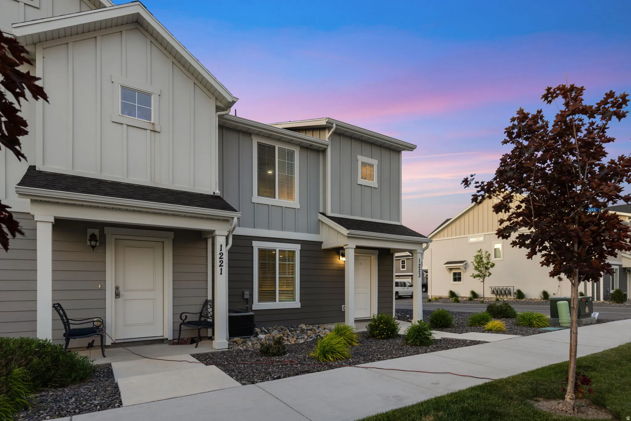Modern multi-story exterior featuring two-tone siding, a covered entry porch, and a sidewalk leading to the front door