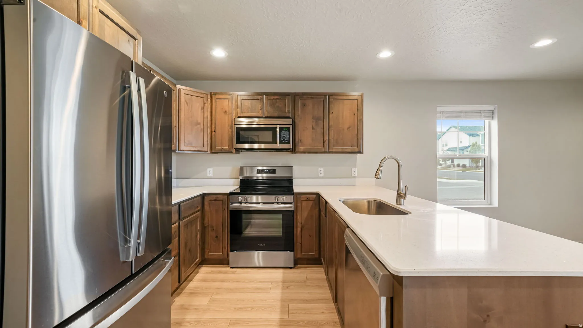 Kitchen featuring wood-finish cabinetry, stainless steel appliances, and light-toned countertops