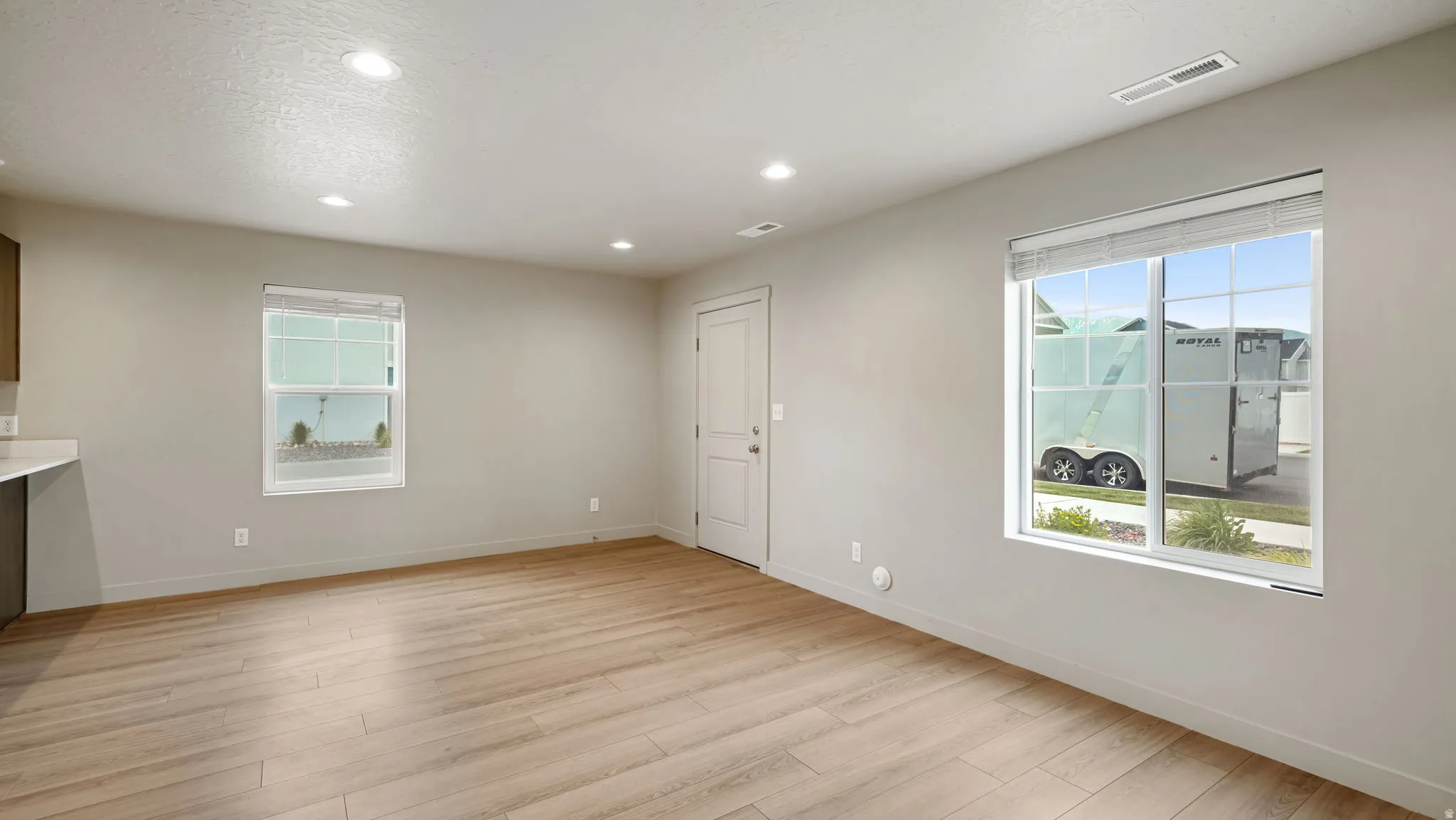 Spacious room featuring wood-finish flooring, recessed lighting, and ample natural light from multiple windows