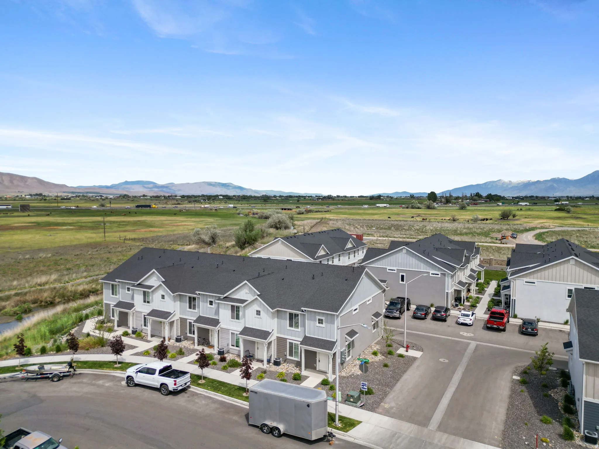 Contemporary townhome development featuring light gray siding with white trim, dark shingled roofs, and individual front entrances