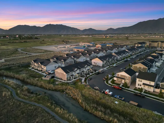 Residential neighborhood featuring a paved street, uniform housing styles, and mountain backdrop