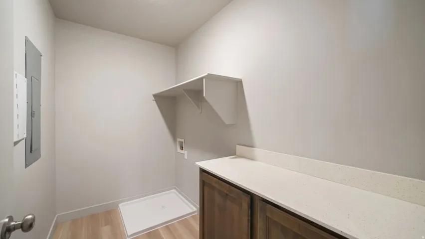 Utility room featuring wood-finish flooring, white walls, and a built-in shelf
