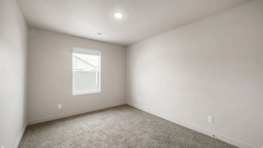 Room featuring light gray carpet, neutral wall paint, and a white window with blinds