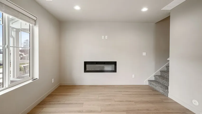 Spacious room featuring wood-finish flooring and an inset electric fireplace