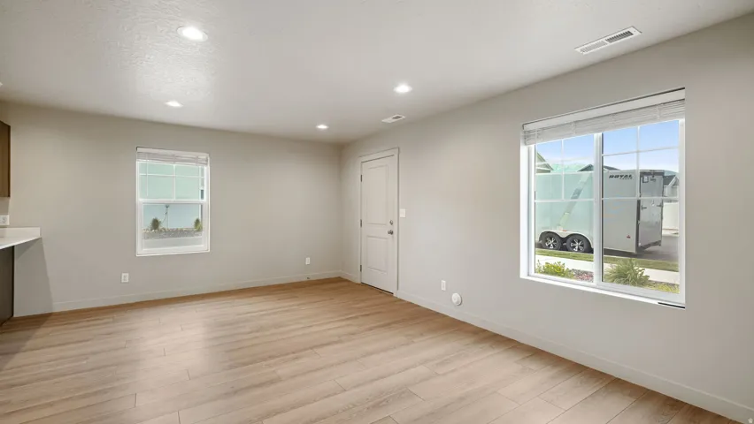 Spacious room featuring wood-finish flooring, recessed lighting, and ample natural light from multiple windows