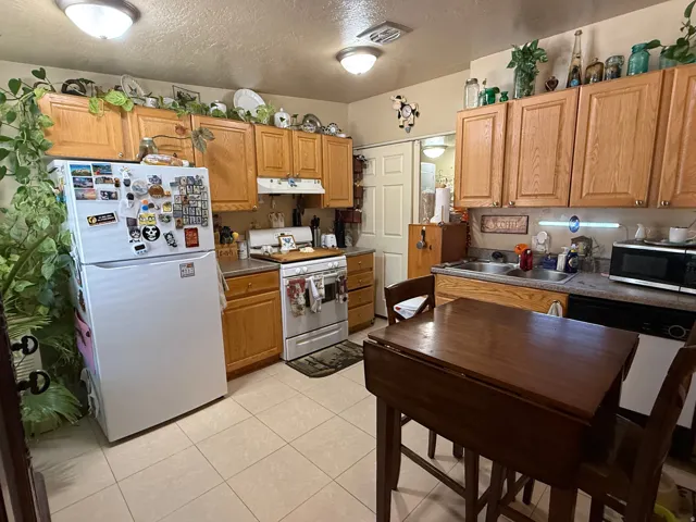 Kitchen featuring wood-finish cabinetry, tile flooring, and a double basin sink