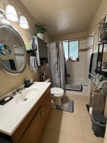 Bathroom featuring a single vanity with wood-finish cabinetry and a white countertop, oval mirror, and a bathtub/shower combination with a tiled surround