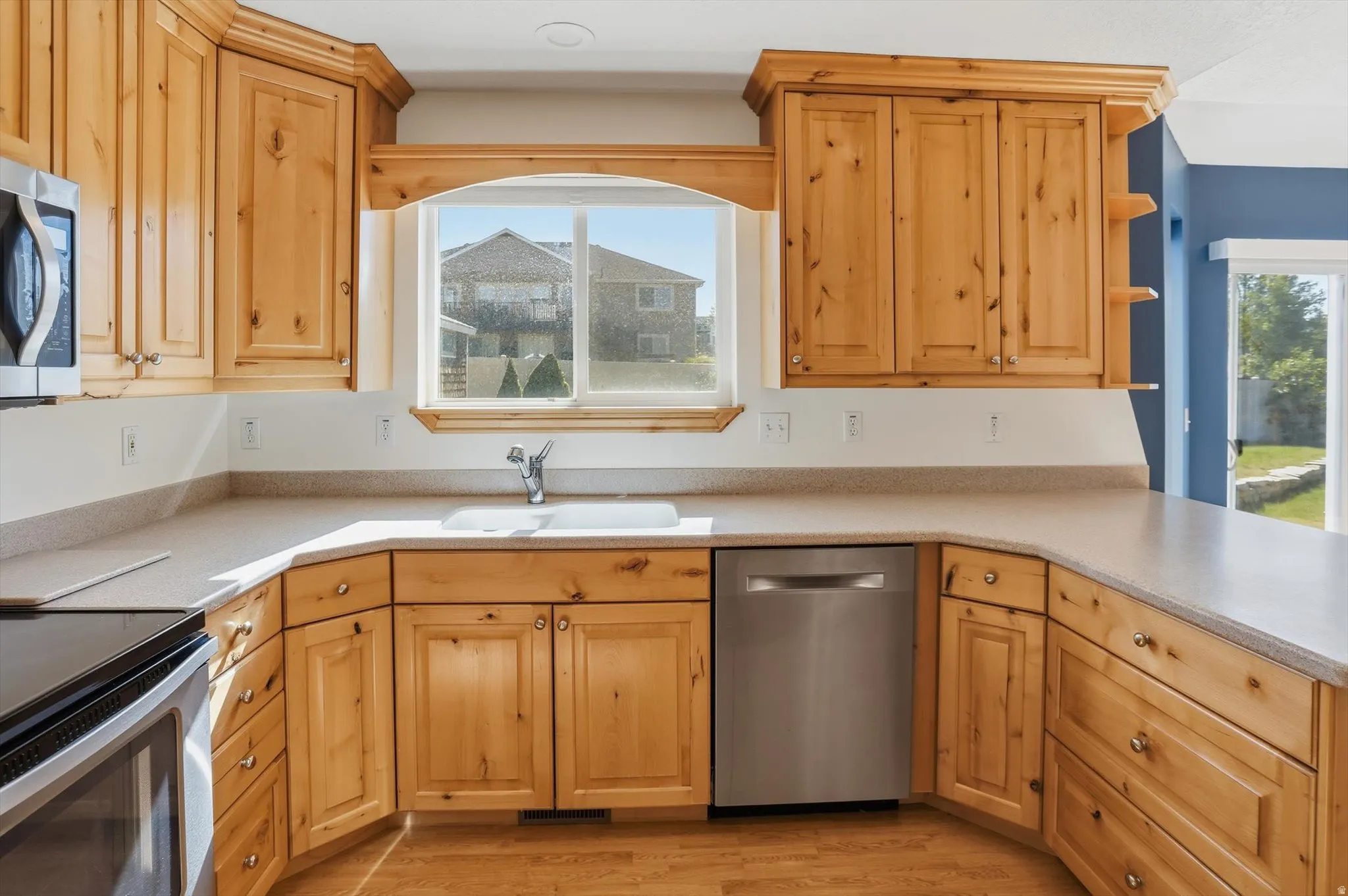 Kitchen featuring a stainless steel microwave, wood cabinetry, a built-in dishwasher, and a double basin sink