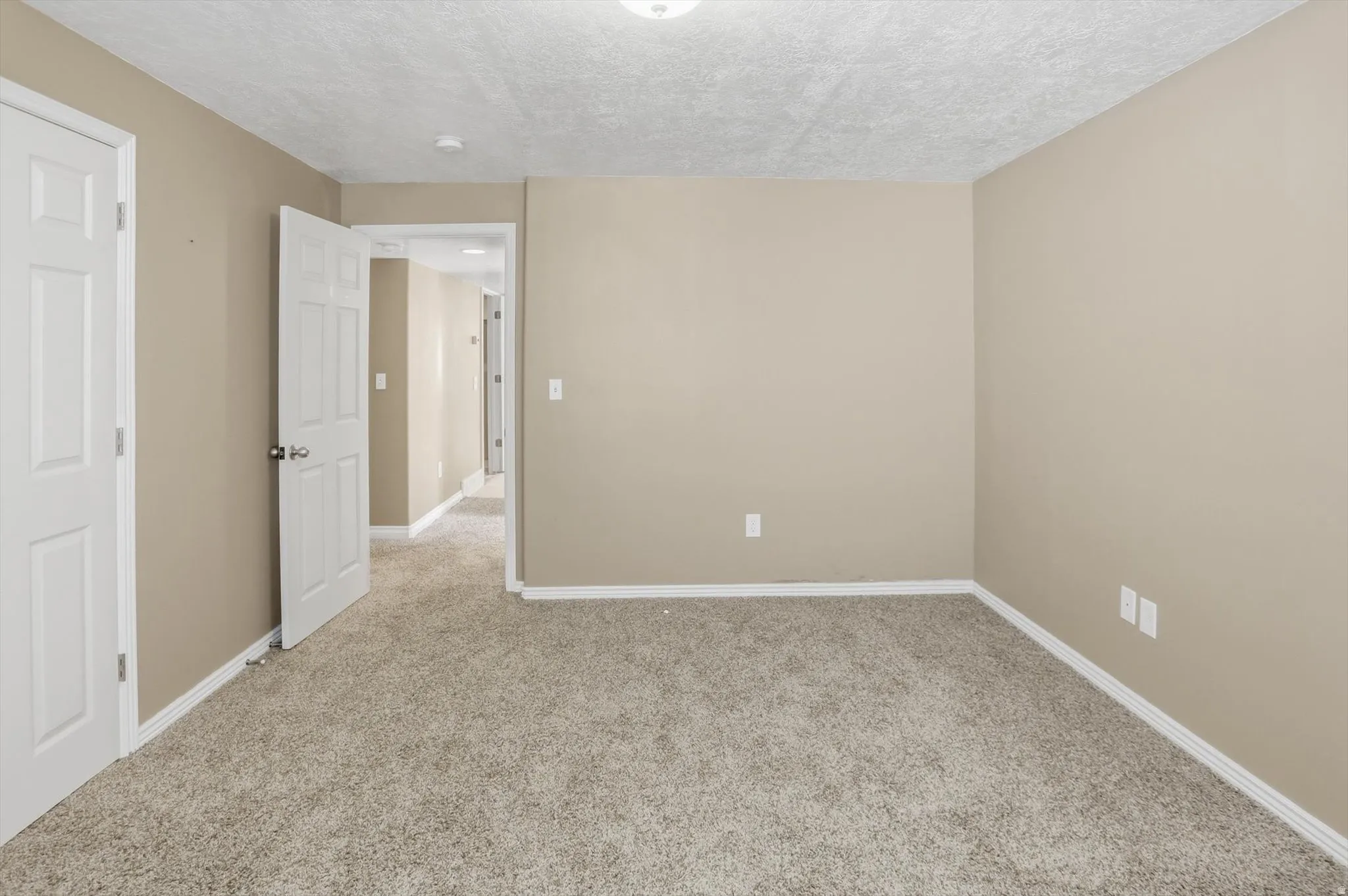 Carpeted room featuring neutral-toned walls, white trim, and a white six-panel door