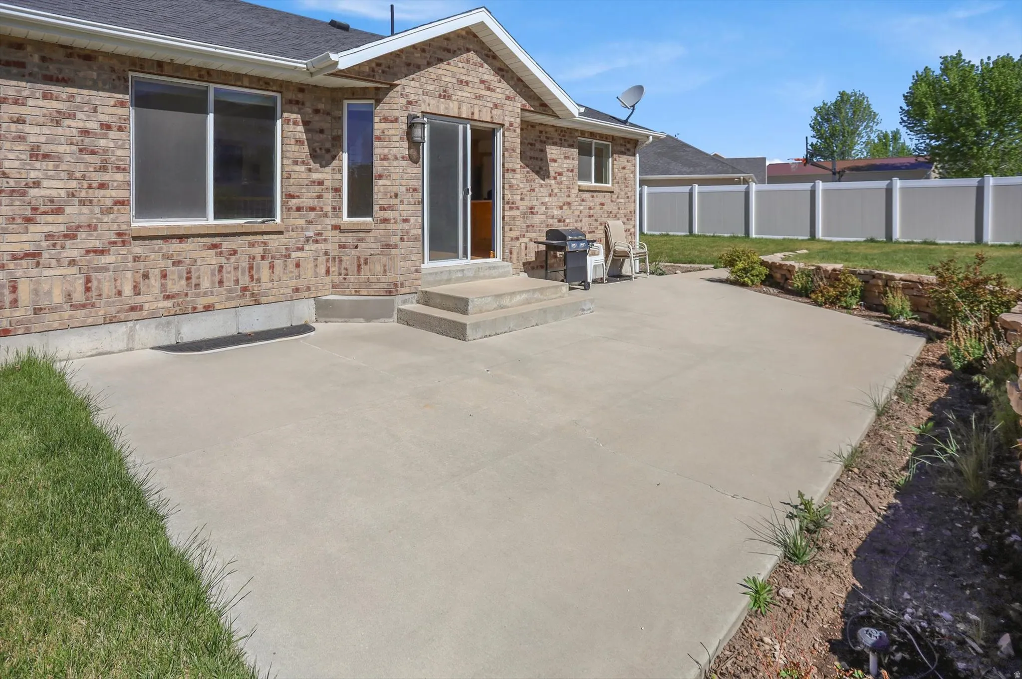 Expansive concrete patio with direct outdoor access via a sliding glass door