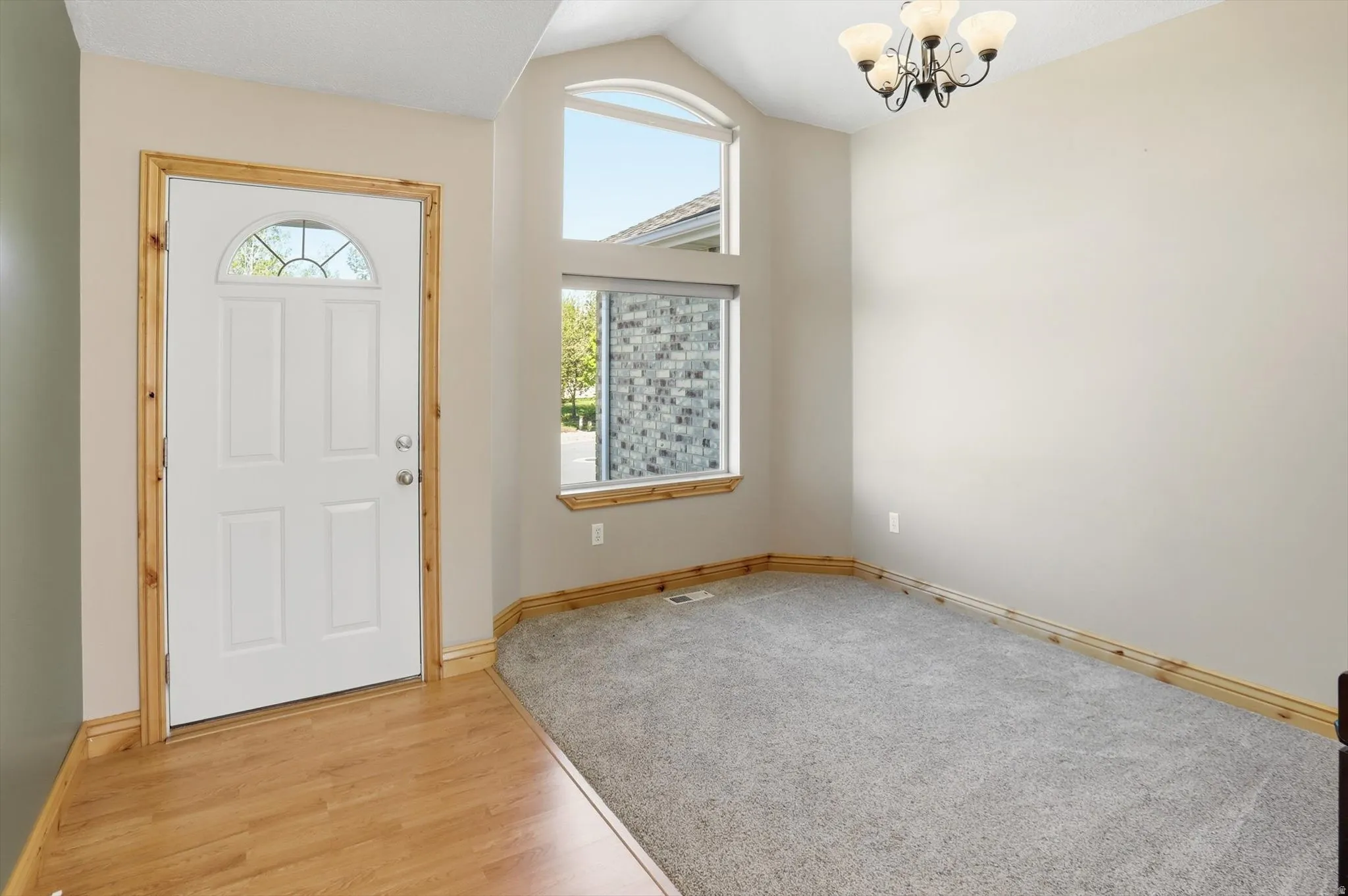 Entryway featuring a white paneled door with an arched glass insert, wood-finish flooring, and a decorative chandelier