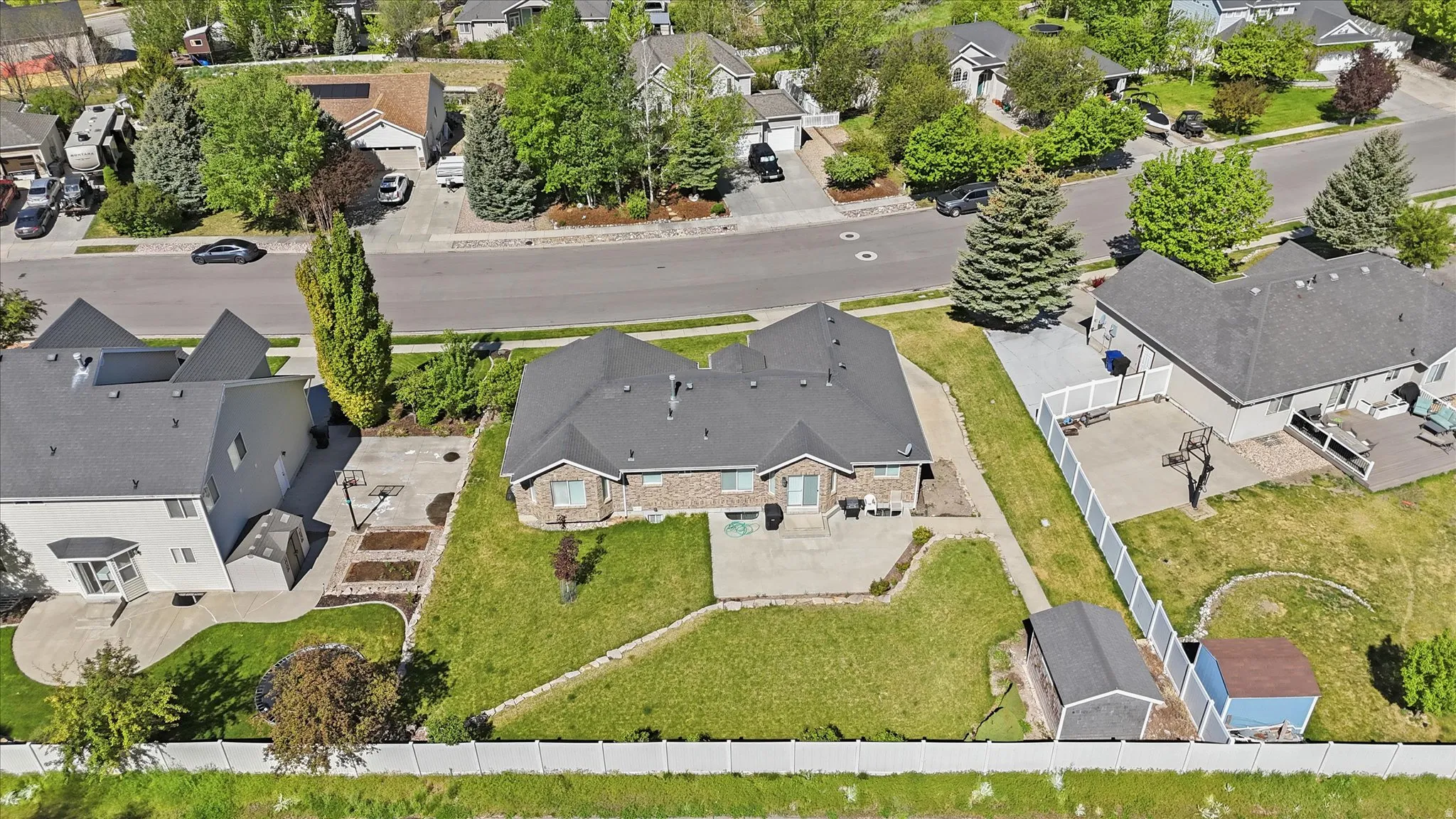 Spacious residential property featuring a large green lawn, a light gray exterior with brick accents, and a dark shingled roof